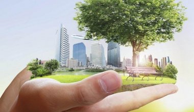 Image of a hand carefully holding a city and a tree in a green-space setting